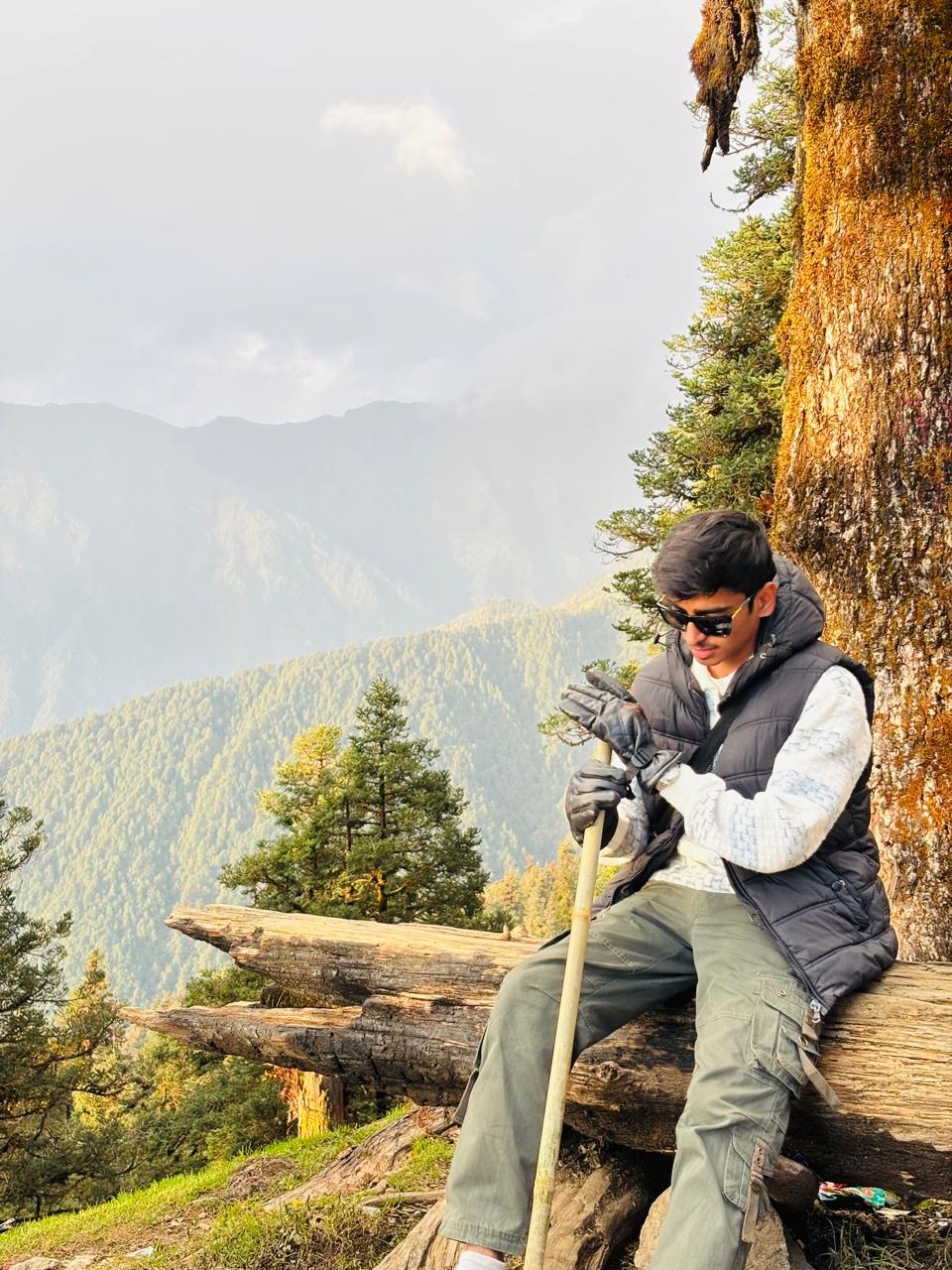 Parth seated on a fallen log in a forested Uttarakhand hillside